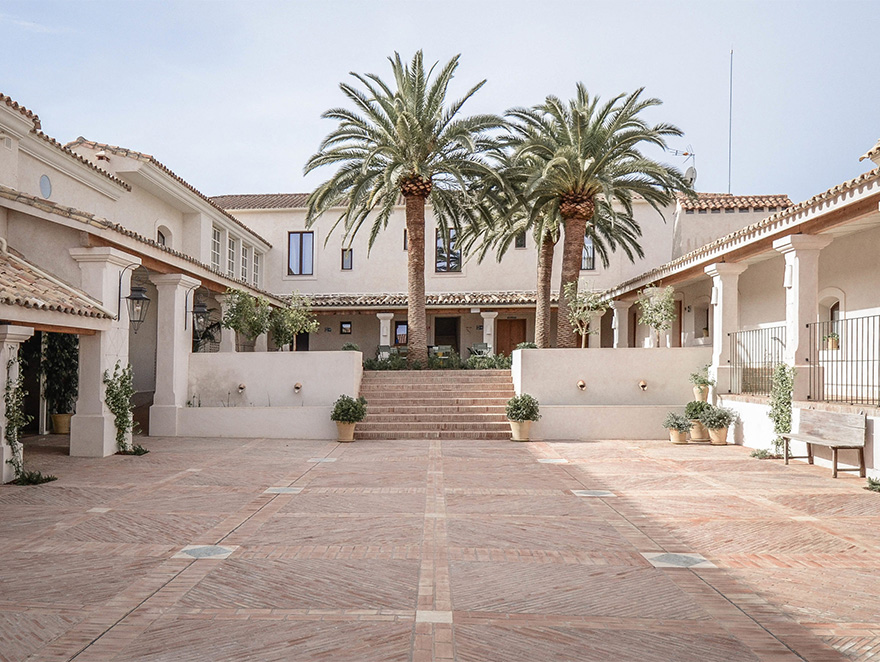 Patio central amplio con palmeras y arquitectura andaluza en una finca de retiro