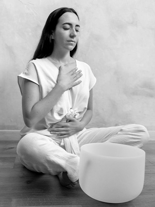 Mujer practicando respiración consciente con un cuenco de sonido en primer plano.